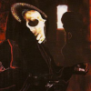 A figure with a high collar wearing an animal skull mask.